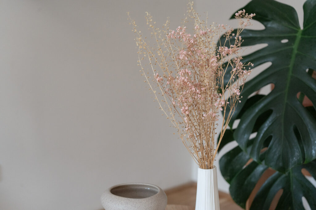 Duftlampe mit Trockenblumen und Monstera in einem ruhigen Wohnraum.