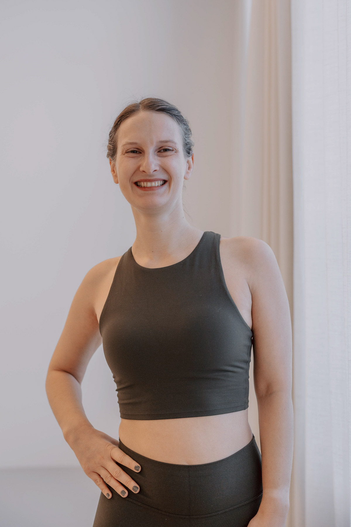 Verena von RootFlow lächelt in einem hellen Yogastudio in die Kamera.
