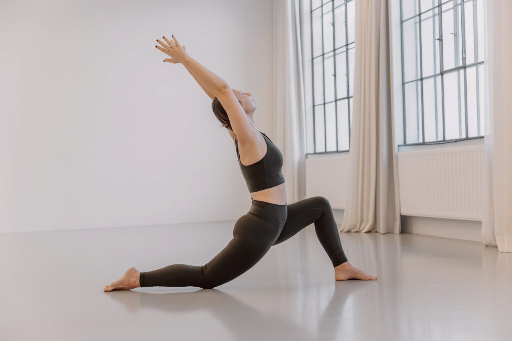Verena in einer Low-Lunge-Yogahaltung in einem hellen Yogaraum.