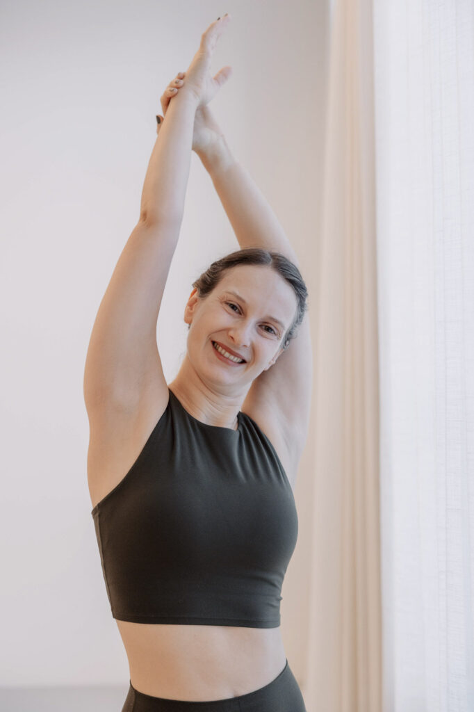 Verena in einer seitlichen Yoga-Dehnung im hellen Yogastudio.