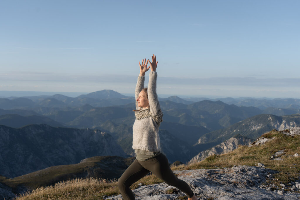 Verena von RootFlow praktiziert Yoga auf dem Hochschwab mit Bergpanorama im Hintergrund.
